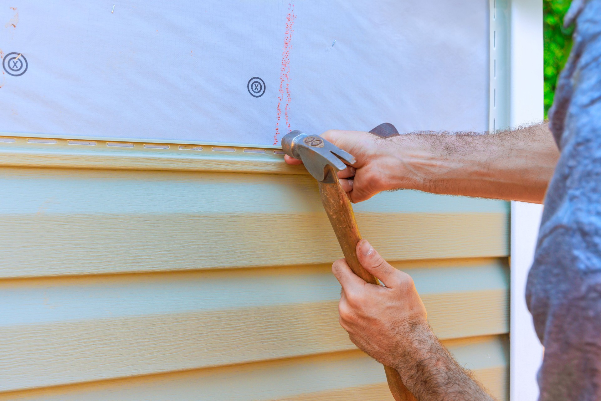 Home improvement task involves installing vinyl siding on house in residential area